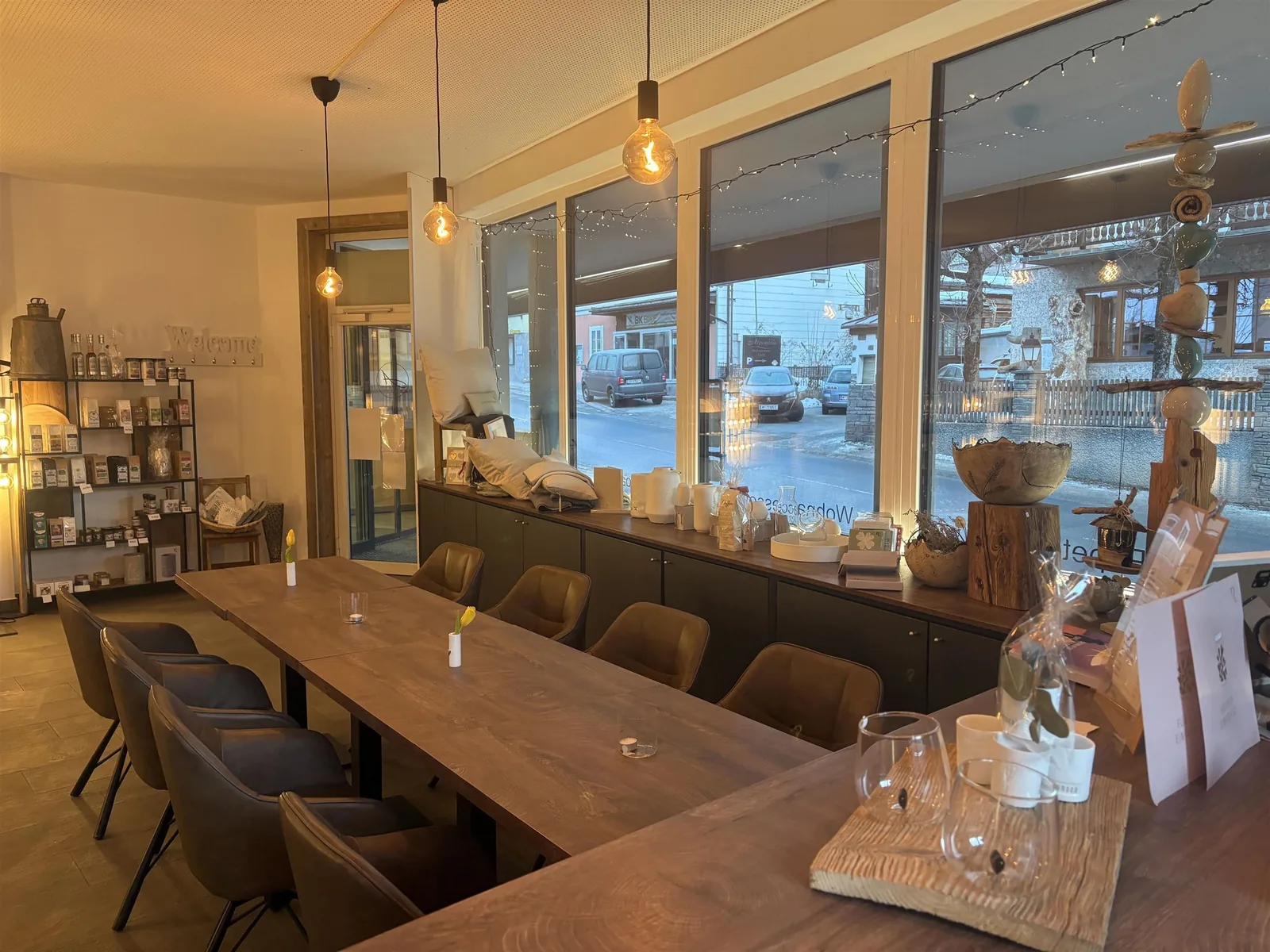 Langer Holztisch am Fensterband des Cafés, links Regale mit Deko