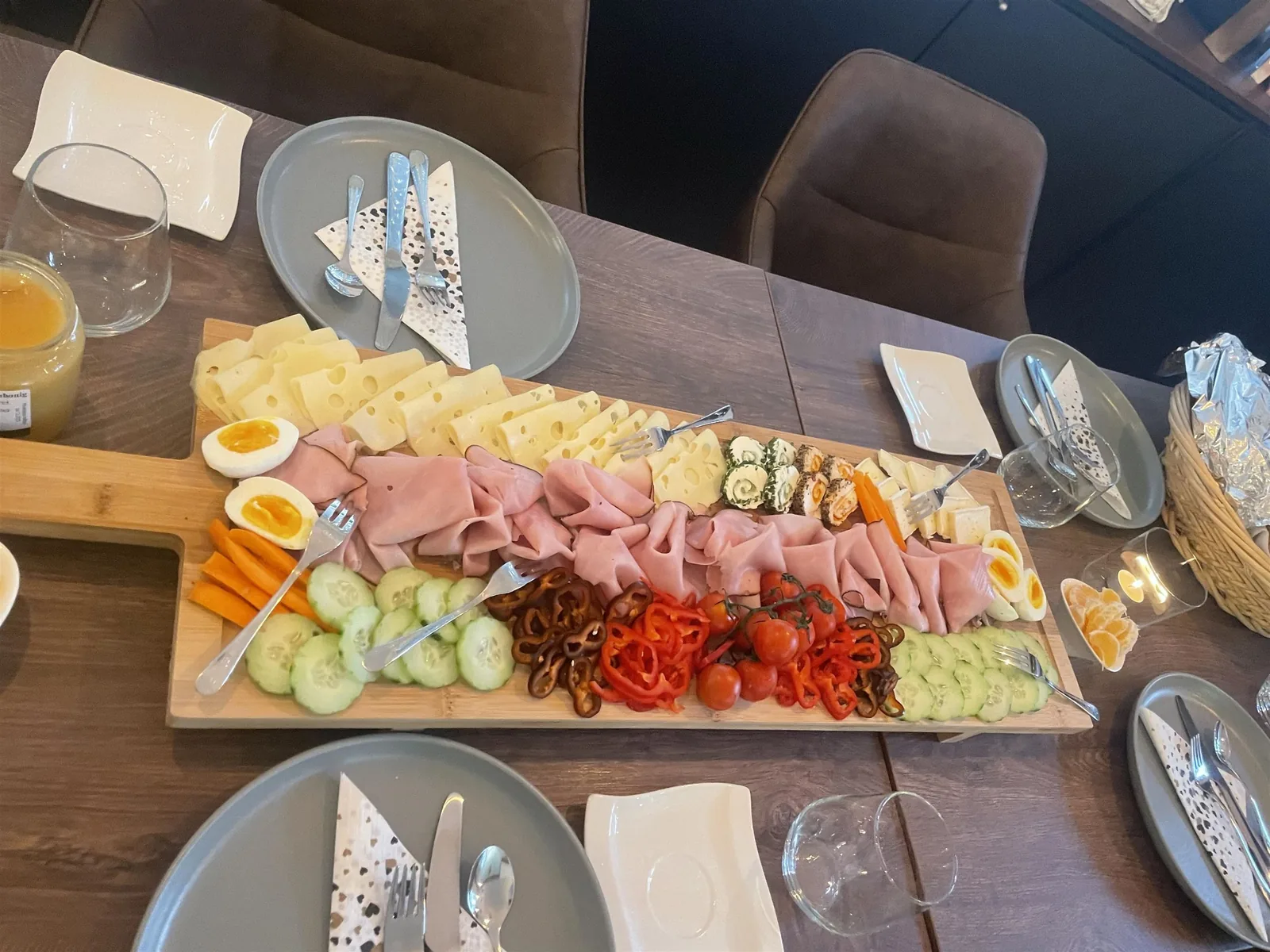 Holzbrett mit Käse, Schinken, Ei, Gemüse und Salzgebäck