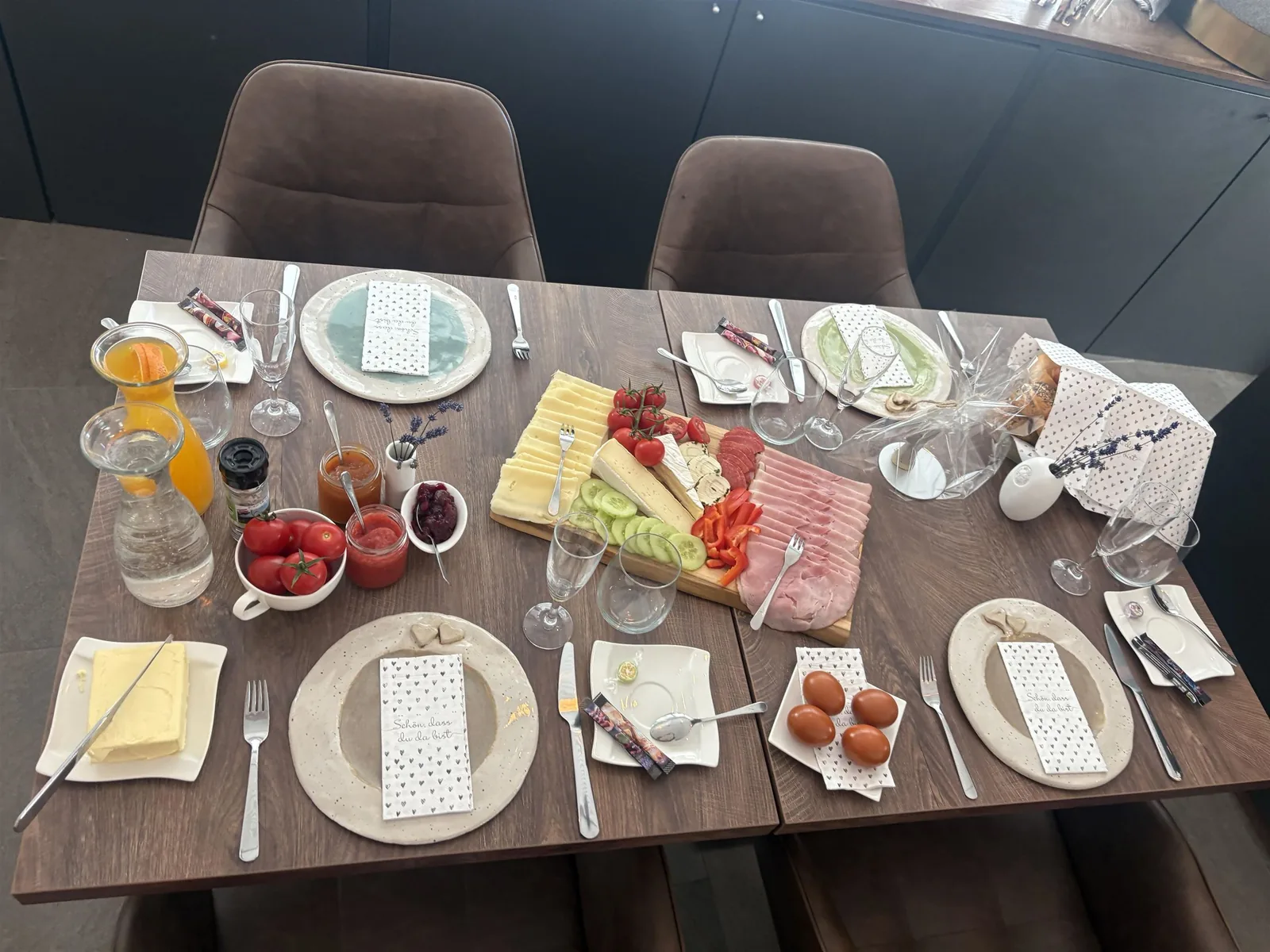 Gedeckter Frühstückstisch mit Saft, Marmeladen und einer Jause